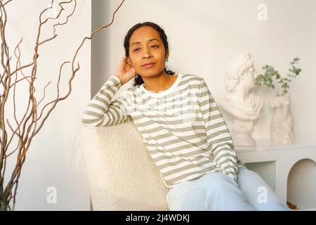 Young beautiful African-American female thoughtfully looking at window in lounge Stock Photo