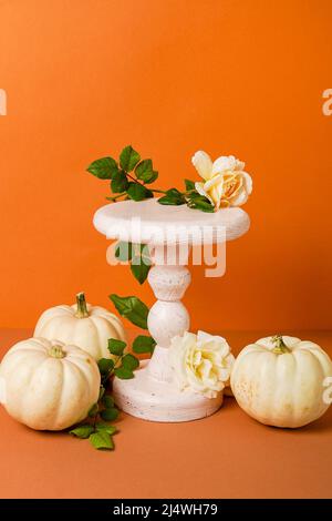 Halloween background podium display with pumpkins and flowers on orange background. Cosmetic, beauty product promotion autumn pedestal Stock Photo