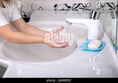 A child washes his hands with soap under the tap, close-up Stock Photo