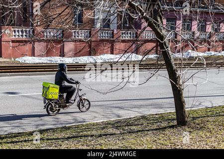 Moscow, Russia - April 14, 2022: delivery service worker rides an electric bike. High quality photo Stock Photo