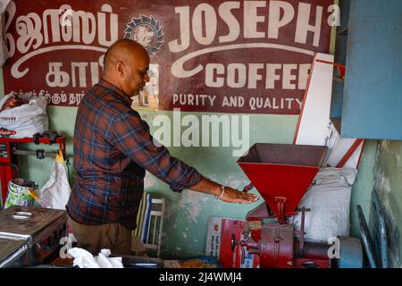 Coffee salesman working the grinder  in his shop in Trichy, Tamil Nadu, India Stock Photo