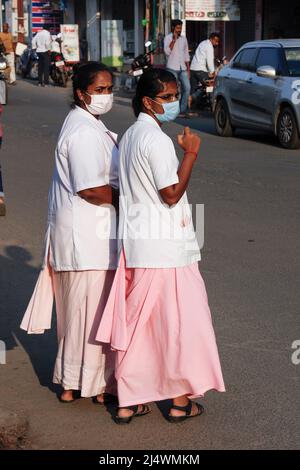Two young hospital nurses waiting to cross the road in Trichy, Tamil Nadu, India Stock Photo
