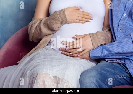 Husband, wife holding hands on pregnant belly. Stock Photo