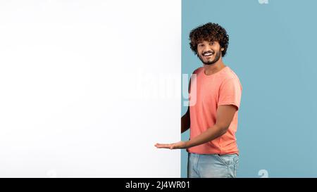 Smiling young hindu man showing blank advertising board Stock Photo