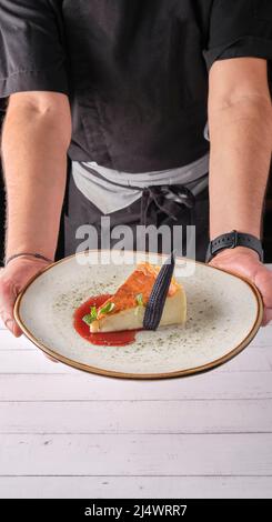Chef presenting plate of New York cheesecake or classic cheesecake with fresh, appetizing healthy. Stock Photo