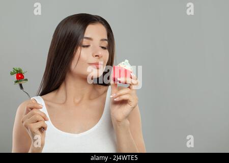 Young woman making choice between healthy and unhealthy food Stock Photo