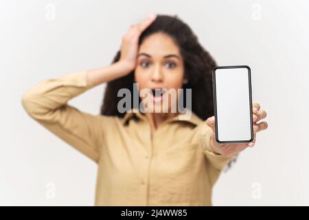 Incredible promotion. Selective focus at empty smartphone screen in hand of amazed African-American woman isolated on white, surprised multiracial lady holding phone with blank display, copy space Stock Photo