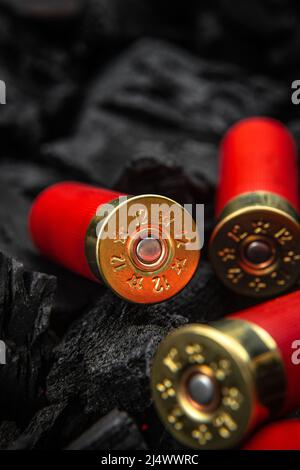 Shotgun cartridges on charcoal. Ammunition for 12 gauge smoothbore weapons. Hunting ammunition. Dark background. Stock Photo