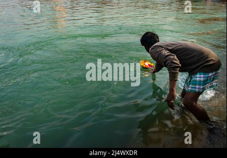 man offering flower pot to the holy river at morning from flat angle image is taken at har ki pauri haridwar uttrakhand india on Mar 15 2022. Stock Photo