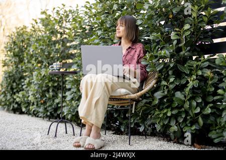 Woman works on laptop computer at garden Stock Photo