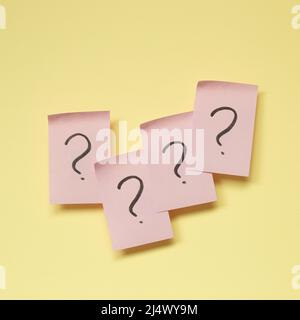 Question mark on pink memo paper on yellow background Stock Photo