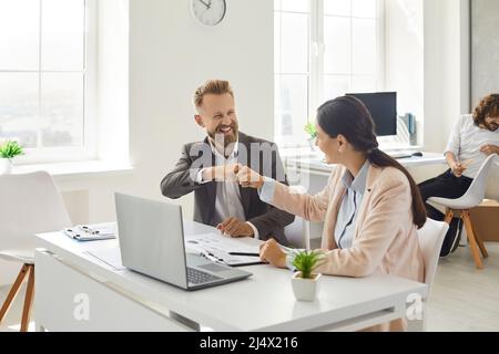 Two happy young business people making a business deal, fist bumping and smiling Stock Photo