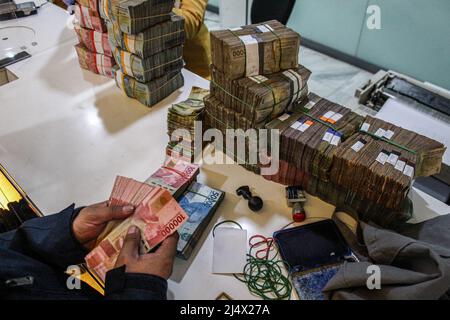 Bandung, Indonesia. 18th Apr, 2022. A customer counts money to be deposited at Mandiri Mikro Business Unit Bandung Braga in Bandung. Bank Mandiri Region VI/Java 1 prepares cash needs of around IDR 6.6 trillion to anticipate the increase in people's cash needs in West Java. The value includes IDR 6.1 trillion for charging 1207 ATMs and Rp 535 billion of new money for customer needs over the next 33 days on April 7 - May 9, 2022, during the Ramadan period and ahead of Eid al-Fitr 1443 H. Credit: SOPA Images Limited/Alamy Live News Stock Photo