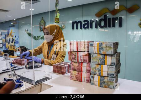 Bandung, Indonesia. 18th Apr, 2022. A woman arranges bundles of Indonesian rupiah banknotes at Mandiri Mikro Business Unit Bandung Braga in Bandung. Bank Mandiri Region VI/Java 1 prepares cash needs of around IDR 6.6 trillion to anticipate the increase in people's cash needs in West Java. The value includes IDR 6.1 trillion for charging 1207 ATMs and Rp 535 billion of new money for customer needs over the next 33 days on April 7 - May 9, 2022, during the Ramadan period and ahead of Eid al-Fitr 1443 H. Credit: SOPA Images Limited/Alamy Live News Stock Photo