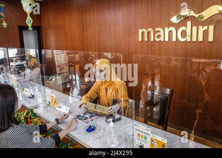 Bandung, Indonesia. 18th Apr, 2022. A woman arranges bundles of Indonesian rupiah banknotes at Mandiri Unit Mikro Bandung Alun-Alun in Bandung. Bank Mandiri Region VI/Java 1 prepares cash needs of around IDR 6.6 trillion to anticipate the increase in people's cash needs in West Java. The value includes IDR 6.1 trillion for charging 1207 ATMs and Rp 535 billion of new money for customer needs over the next 33 days on April 7 - May 9, 2022, during the Ramadan period and ahead of Eid al-Fitr 1443 H. Credit: SOPA Images Limited/Alamy Live News Stock Photo