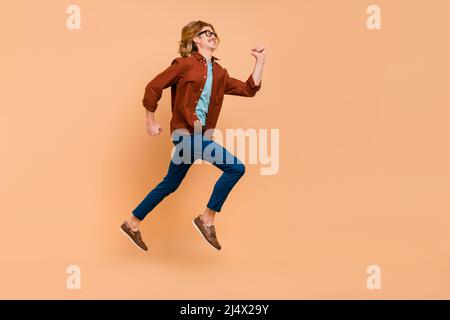 Full length body size view of attractive cheerful anergetic guy jumping running bargain isolated over beige pastel color background Stock Photo