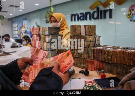 Bandung, Indonesia. 18th Apr, 2022. A customer counts money to be deposited at Mandiri Mikro Business Unit Bandung Braga in Bandung. Bank Mandiri Region VI/Java 1 prepares cash needs of around IDR 6.6 trillion to anticipate the increase in people's cash needs in West Java. The value includes IDR 6.1 trillion for charging 1207 ATMs and Rp 535 billion of new money for customer needs over the next 33 days on April 7 - May 9, 2022, during the Ramadan period and ahead of Eid al-Fitr 1443 H. (Photo by Algi Febri Sugita/SOPA Images/Sipa USA) Credit: Sipa USA/Alamy Live News Stock Photo