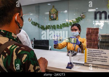 Bandung, Indonesia. 18th Apr, 2022. A woman shows bundles of 50000 IDR and 20000 IDR banknotes at Mandiri Mikro Business Unit Bandung Braga in Bandung. Bank Mandiri Region VI/Java 1 prepares cash needs of around IDR 6.6 trillion to anticipate the increase in people's cash needs in West Java. The value includes IDR 6.1 trillion for charging 1207 ATMs and Rp 535 billion of new money for customer needs over the next 33 days on April 7 - May 9, 2022, during the Ramadan period and ahead of Eid al-Fitr 1443 H. (Photo by Algi Febri Sugita/SOPA Images/Sipa USA) Credit: Sipa USA/Alamy Live News Stock Photo