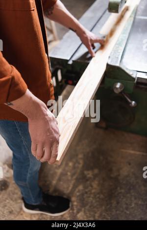cropped view of carpenter working with board on jointer machine Stock Photo