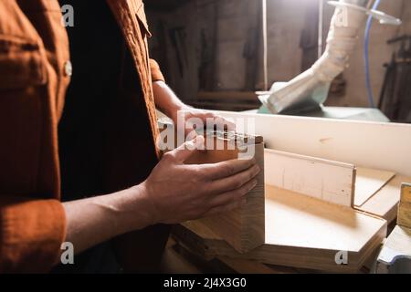 cropped view of woodworker checking board in workshop Stock Photo