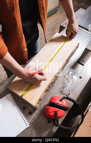 partial view of furniture designer with pencil measuring board on workbench Stock Photo