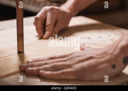 cropped view of blurred carpenter cutting plywood with band saw Stock Photo