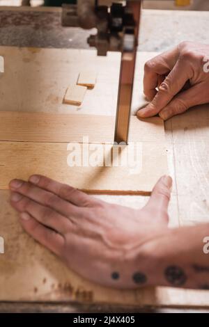 cropped view of joiner cutting plywood with band saw Stock Photo
