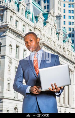 Portrait of successful businessman. Dressing formally in blue suit, tie, wearing ear stub, a young black, modern guy standing in the front of vintage Stock Photo