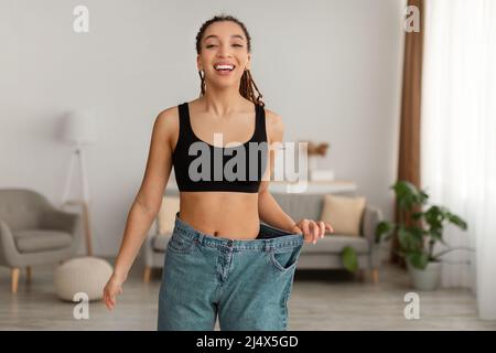 Happy Fit African American Woman Wearing Old Big Jeans Indoor Stock Photo