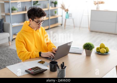 Focused asian man working on laptop at home Stock Photo