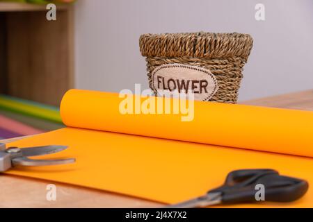 Close-up of a roll of orange wrapping paper, scissors, pruning