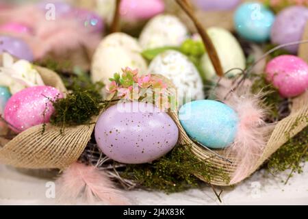 Easter eggs and feathers in wicker basket with colorful decorations. Festive background for greeting card Stock Photo