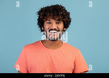 Portrait of positive handsome indian young man on blue Stock Photo