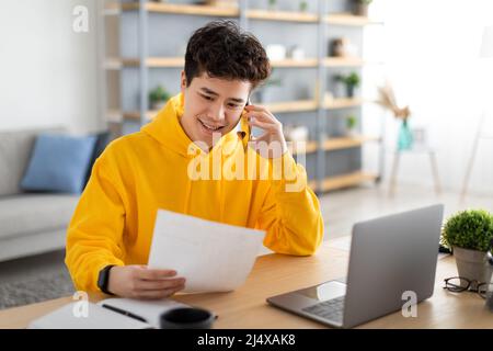 Asian man holding paper reading report talking on phone Stock Photo
