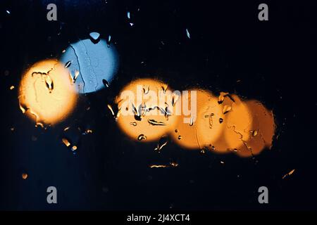 Raindrops on the glass with the bokeh of night light Stock Photo