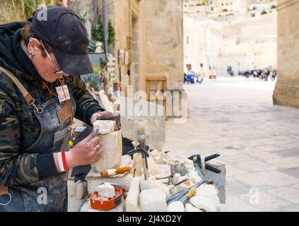 artisan woman work on piece of stone in street to create object ornaments stone Stock Photo
