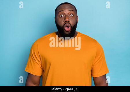 Photo of impressed funny guy dressed orange t-shirt big eyes open mouth isolated blue color background Stock Photo