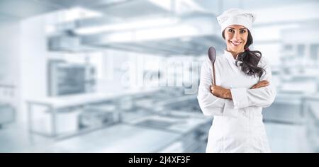 Female chef standing with wooden ladle in kitchen restaurant. Stock Photo