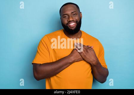 Portrait of attractive cheerful guy touching heart enjoying feeling good isolated over bright blue color background Stock Photo