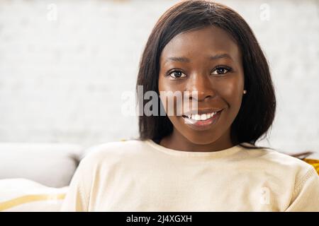 Close-up portrait on multiracial woman in home interior, charming lady looking at camera and smiles, resting, serene female spends weekend at home Stock Photo