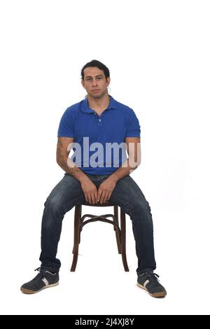 front view of man with ponytail and casual clothing  and tattoos sitting a chair on white background Stock Photo