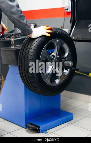 Auto mechanic balances the car wheel on the wheel balancer Stock Photo