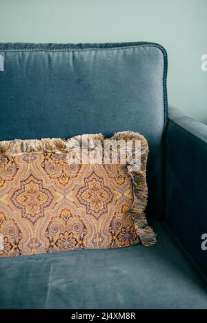 fringed pillow on a blue upholstered sofa Stock Photo