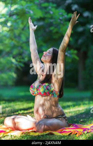 pregnant young woman doing yoga outdoors Stock Photo