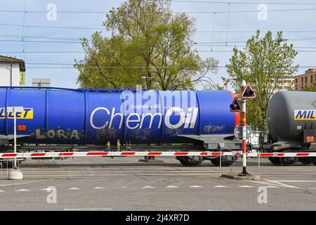 Basel, Switzerland - April 2022: Train of oil tankers crossing a road in the city's port on the Rhine River Stock Photo