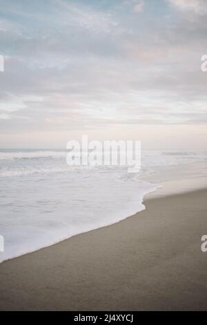 Gentle waves crashing on Carolina Beach with pink and blue sunset Stock Photo