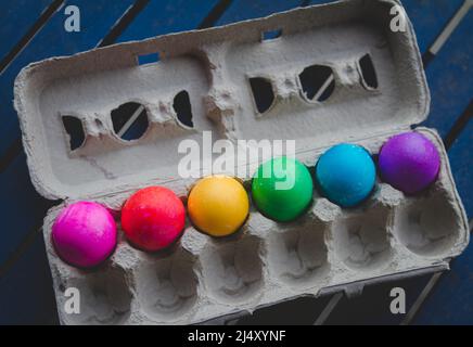 Bright rainbow colored dyed easter Eggs lined up in egg carton Stock Photo