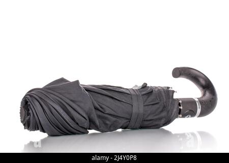 One folded black umbrella, macro, isolated on a white background. Stock Photo