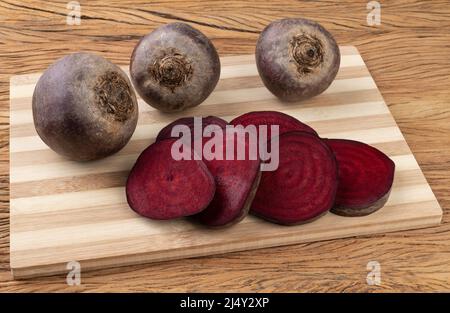 Raw beetroots with cut beetroot on a wooden board. Stock Photo