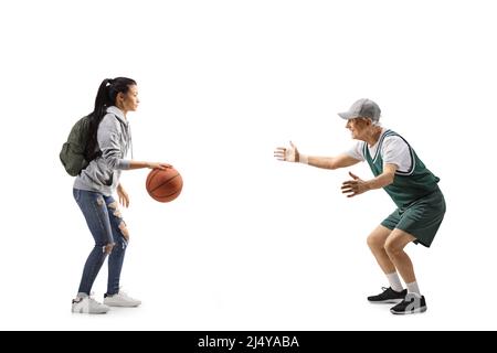 Full length profile shot of a female student and an elderly man playing basketball isolated on white background Stock Photo